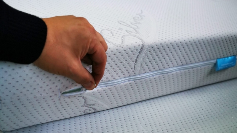 Osoba otvara rajsferšlus na beloj navlaci dušeka