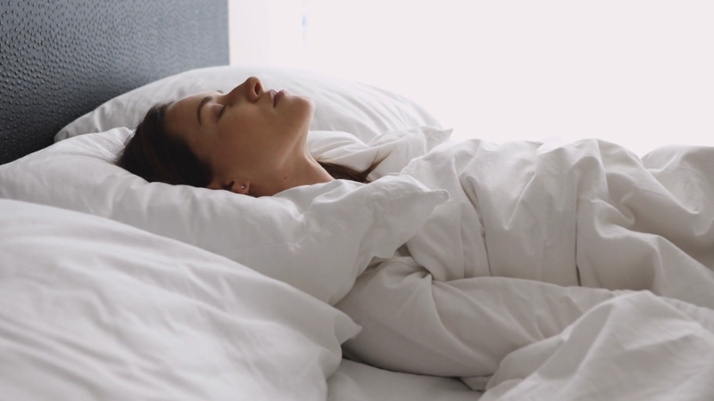 Žena leži na leđima na dušeku u krevetu